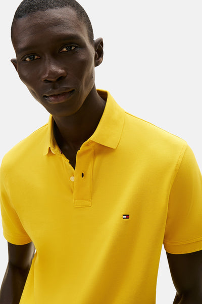 Polo jaune à manches courtes de Tommy Hilfiger, avec logo sur la poitrine, porté par un homme.
