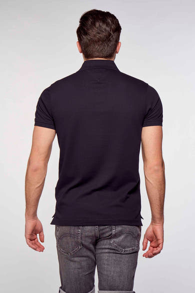 Polo bleu marine de Tommy Hilfiger, coupe classique, porté avec un jean gris délavé, vue de dos.
