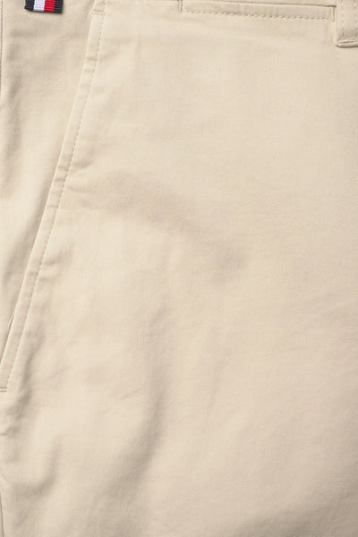 Beige cotton bermuda shorts with side pocket and striped waistband detail, close-up front view