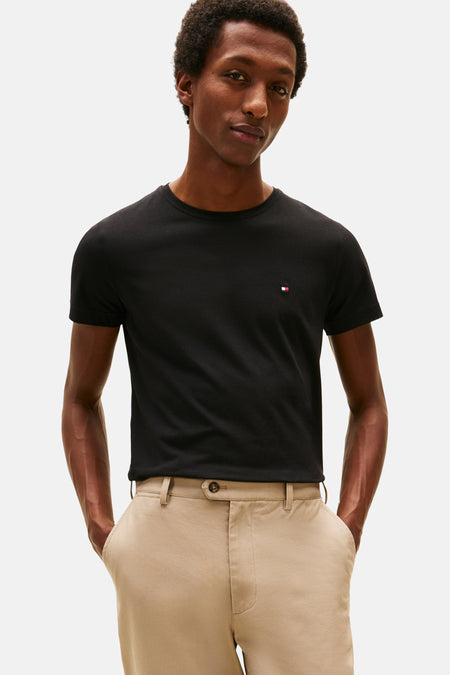 T-shirt noir à manches courtes de Tommy Hilfiger, porté avec un pantalon chino beige.