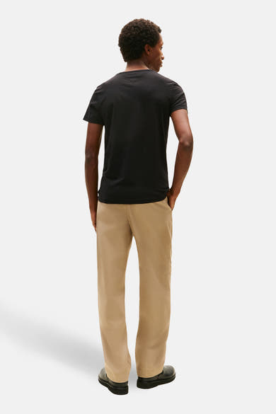 T-shirt à manches courtes noir de TOMMY HILFIGER, vu de dos, porté avec un pantalon beige et des chaussures noires.