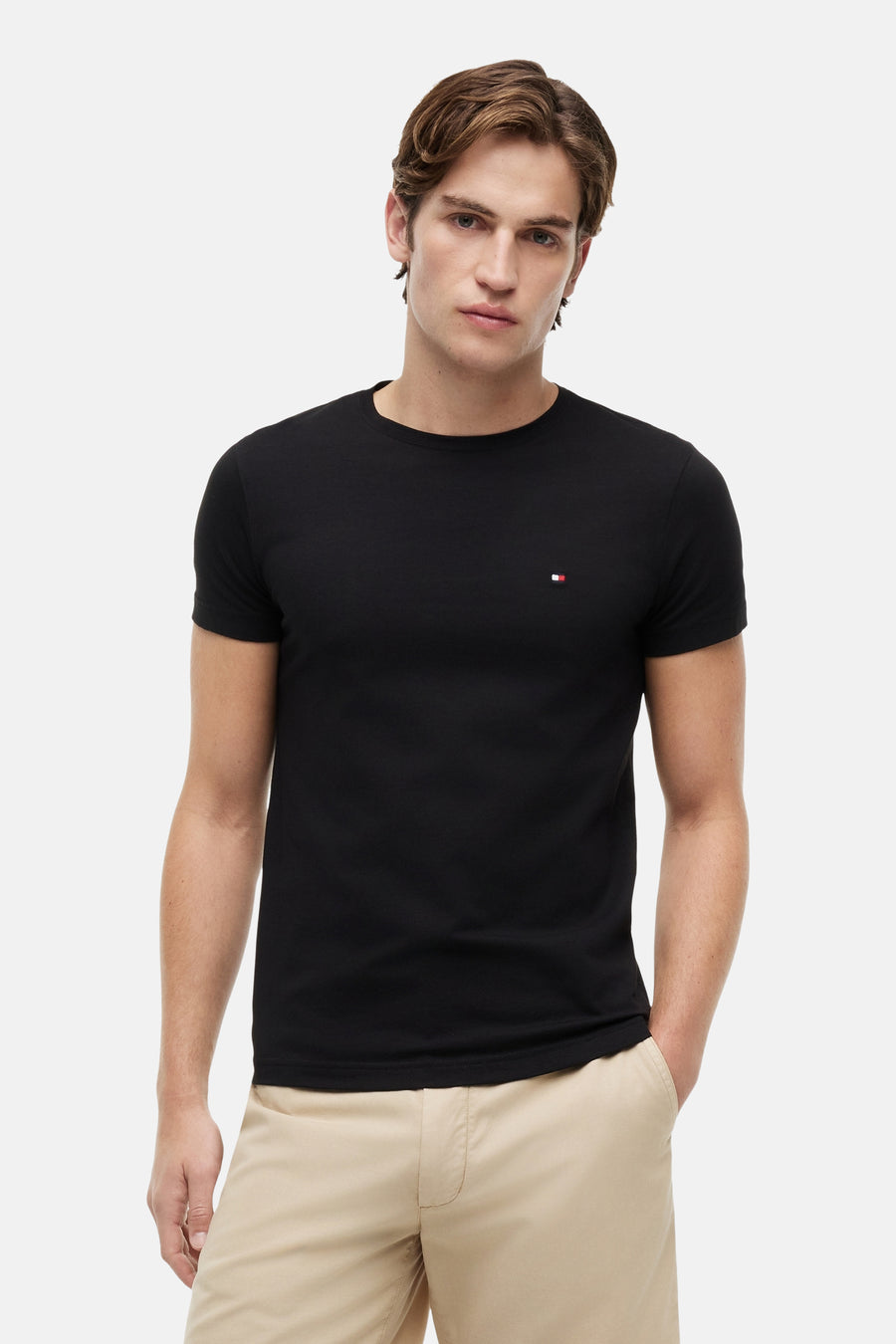 T-shirt à manches courtes noir de Tommy Hilfiger, porté avec un pantalon beige, homme regardant l'objectif.