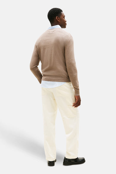 Beige ronde hals trui van TOMMY HILFIGER, gedragen met een lichtblauw gestreept overhemd en een gebroken witte corduroy broek.