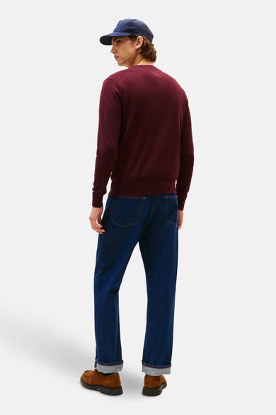 Bordeaux ronde hals trui van TOMMY HILFIGER, gedragen met een blauwe jeans en bruine schoenen.