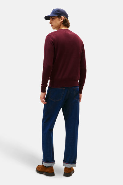 Bordeaux ronde hals trui van TOMMY HILFIGER, gedragen met een blauwe jeans en bruine schoenen.