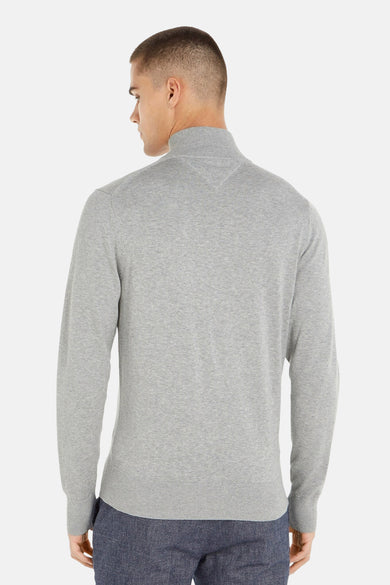 Grijze coltrui van Tommy Hilfiger, stikseldetail bij de kraag, aansluitende pasvorm, gedragen met een marineblauwe broek.