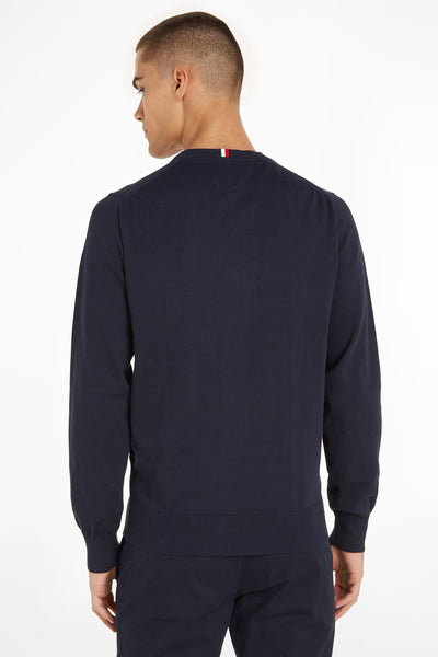 Pull bleu marine de Tommy Hilfiger, détail tricolore sur la nuque, porté avec un pantalon assorti, vue arrière.
