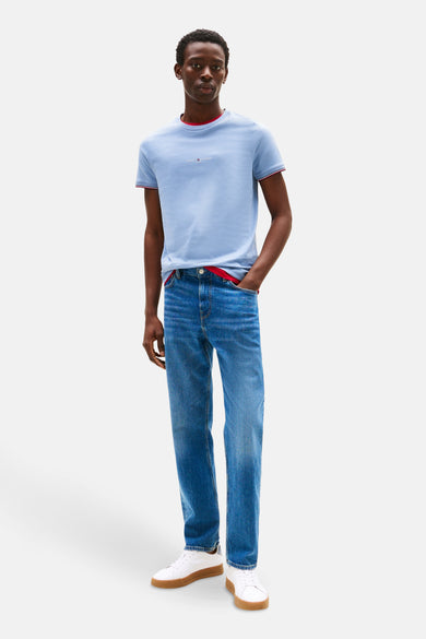 Blauw T-shirt met korte mouwen van TOMMY HILFIGER, met rode bies op de kraag en mouwen, gedragen met een blauwe jeans en witte sneakers.