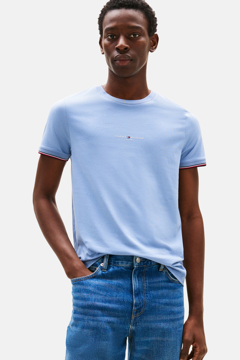 Blauw T-shirt met korte mouwen van TOMMY HILFIGER, met rode en witte strepen op de mouwen en gedragen met een spijkerbroek.