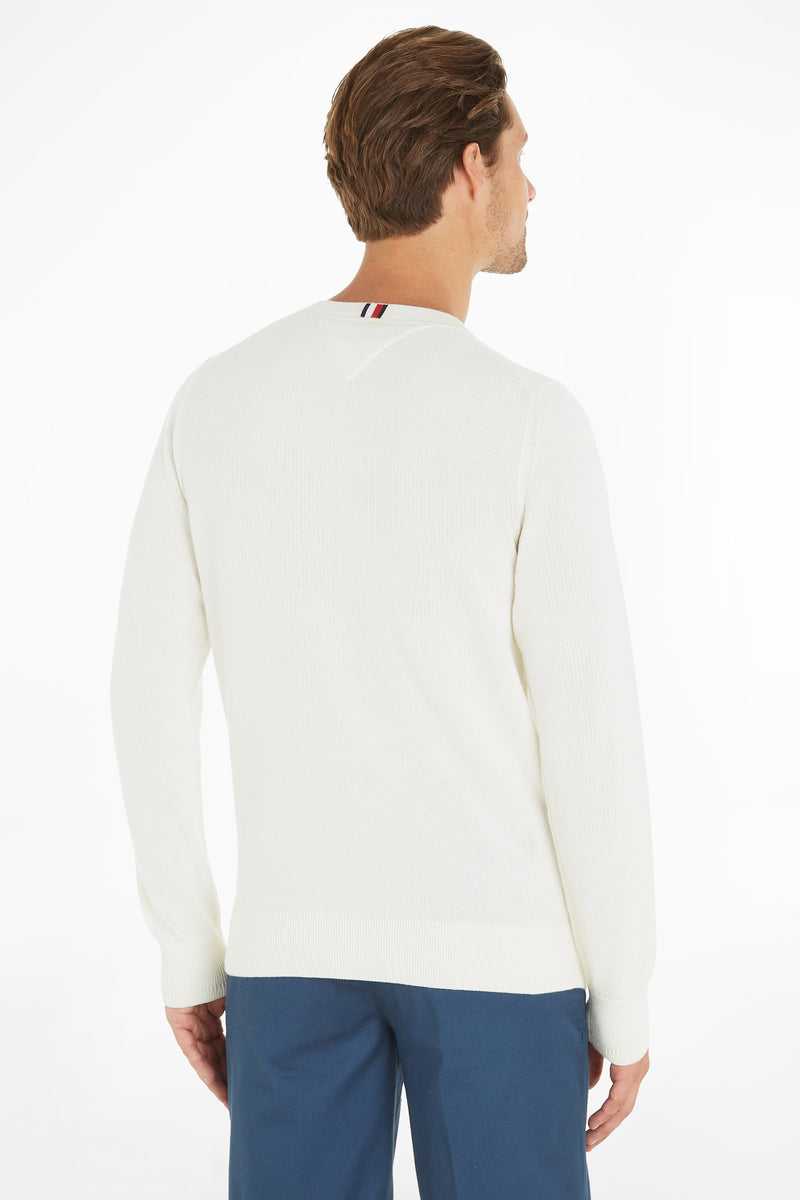 Ecru crewneck sweater with ribbed cuffs and hem, back view showing striped neck trim, worn with blue trousers