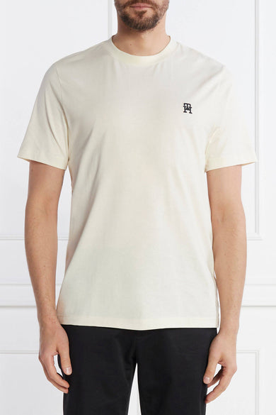 Ecru short-sleeve t-shirt by PH with small black logo on chest, worn with black pants, front view