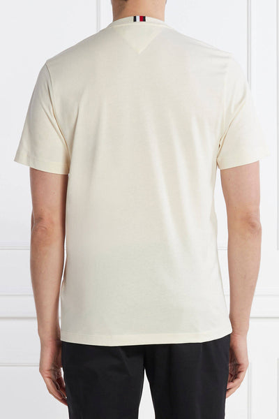Ecru short-sleeve t-shirt by Tommy Hilfiger, back view with striped neck tag, smooth cotton texture, paired with dark trousers.