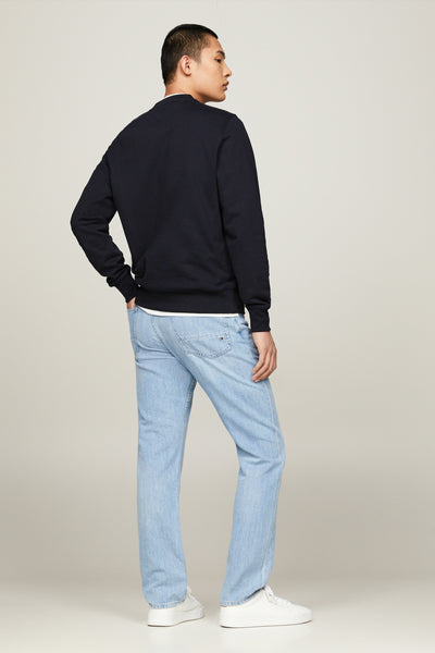 Blauwe Tommy Hilfiger sweater, gedragen met een lichte spijkerbroek en witte sneakers, achterzicht.
