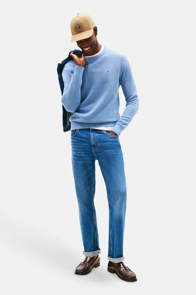 Pull à col rond bleu de TOMMY HILFIGER porté avec un jean et des mocassins en cuir.