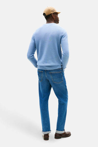 Pull à col rond bleu de TOMMY HILFIGER, porté avec un jean et des mocassins marron, vue de dos.