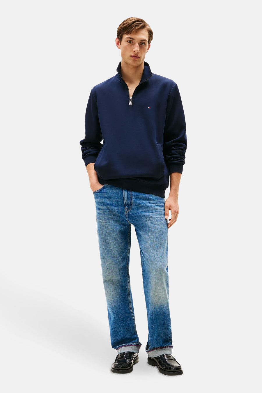 Sweat-shirt bleu foncé de TOMMY HILFIGER, avec col zippé, porté avec un jean et des mocassins noirs.
