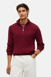 Burgundy cable-knit half-zip sweater by Tommy Hilfiger, featuring ribbed cuffs and collar, worn with white pants and striped tee.