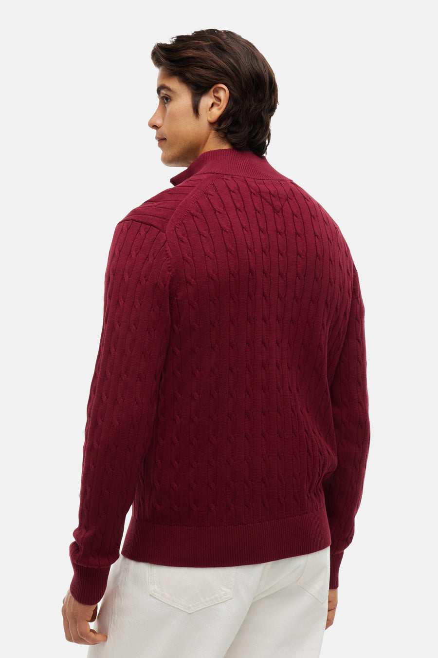 Burgundy ribbed turtleneck sweater with cable knit pattern, side view, worn with white pants