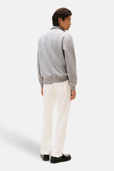 Grijze sweater van TOMMY HILFIGER, gedragen met een witte broek en zwarte loafers, achtergezicht.