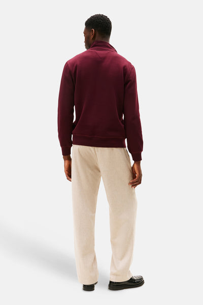 Bordeaux trui met opstaande kraag van TOMMY HILFIGER, gedragen met een wijde beige broek en zwarte loafers.