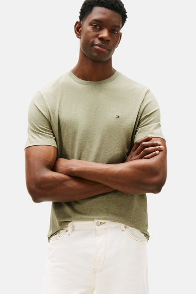 T-shirt vert à manches courtes de TOMMY HILFIGER avec logo subtil, porté avec un pantalon blanc.