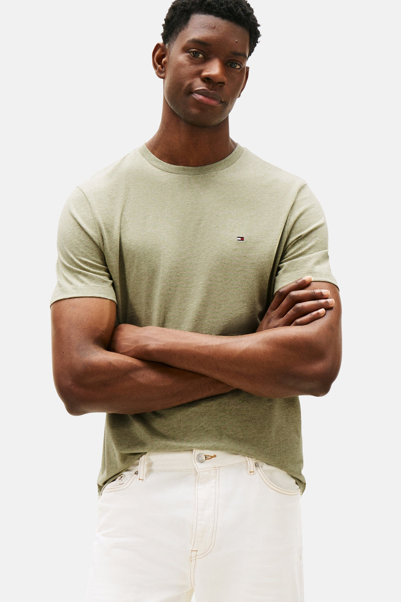 T-shirt vert à manches courtes de TOMMY HILFIGER avec logo subtil, porté avec un pantalon blanc.