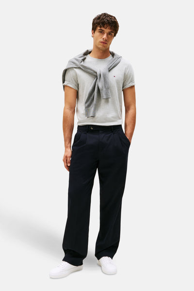 Grijze T-shirt met korte mouwen van TOMMY HILFIGER, met een trui om de nek geknoopt, gedragen met een marineblauwe broek.
