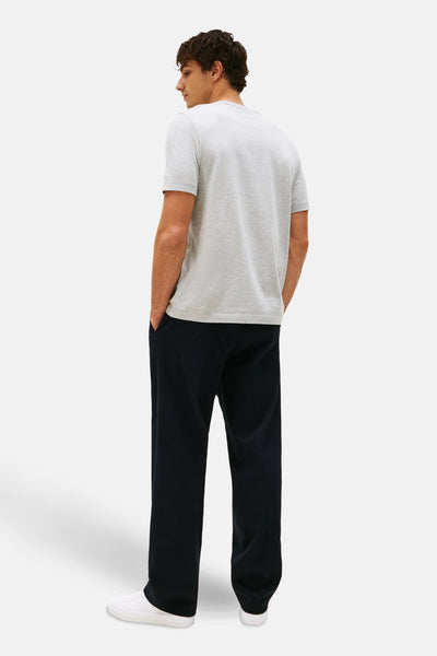 Grijze T-shirt met korte mouwen van TOMMY HILFIGER, gedragen met een wijde marineblauwe broek en witte sneakers, achtergezicht.