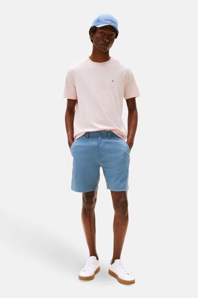 Roze T-shirt met korte mouwen van TOMMY HILFIGER, gedragen met een blauwe hoed en korte broek, en witte schoenen.