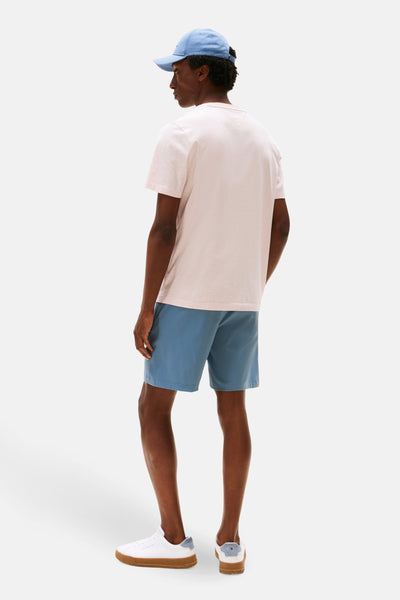 Roze T-shirt met korte mouwen van TOMMY HILFIGER, gedragen met een blauwe korte broek en witte schoenen.