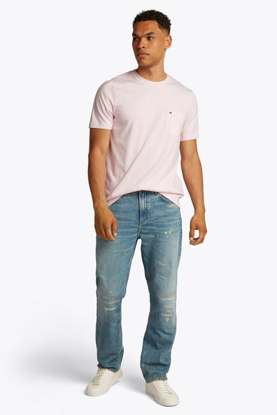 Roze T-shirt met korte mouwen van TOMMY HILFIGER, met borstzak en logovlag, gedragen met een lichtblauwe jeans en witte sneakers.