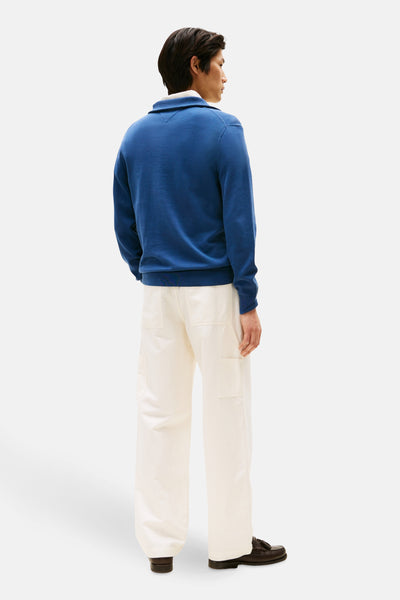 Pull à col roulé bleu de Tommy Hilfiger, porté avec un pantalon blanc et des mocassins marron, vue de dos.
