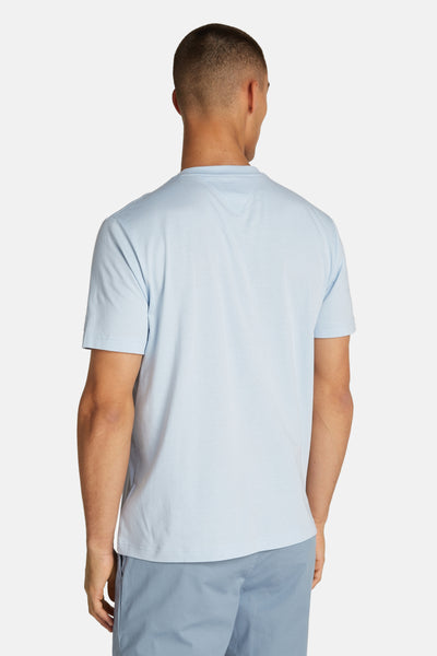 T-shirt bleu à manches courtes de TOMMY HILFIGER, vu de dos, porté avec un pantalon bleu assorti.