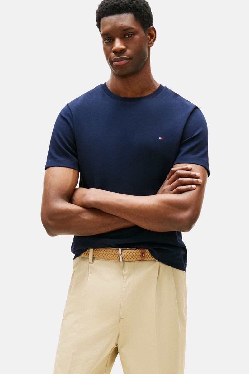 Blauw T-shirt met korte mouwen van Tommy Hilfiger, gedragen met een wijde beige broek en een gevlochten riem.