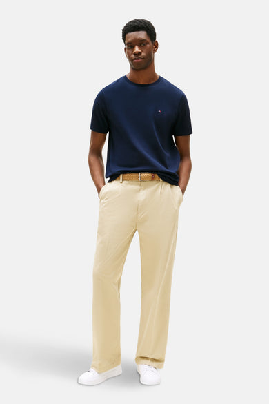 T-shirt bleu à manches courtes de Tommy Hilfiger, porté avec un pantalon beige ample et une ceinture tressée.