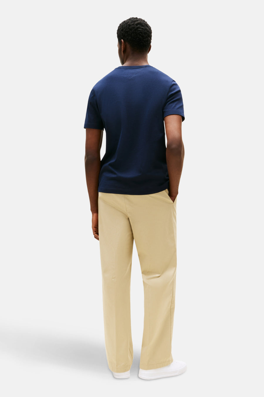T-shirt à manches courtes bleu de TOMMY HILFIGER, porté avec un pantalon beige et des baskets blanches, vue de dos.
