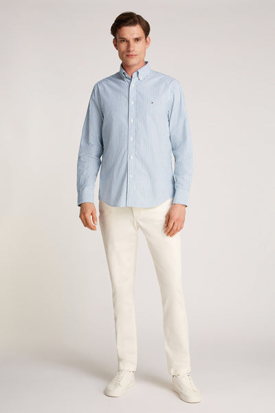 Chemise à manches longues verte rayée de Tommy Hilfiger, portée avec un pantalon blanc et des baskets blanches.