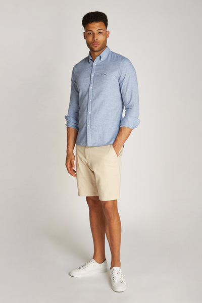 Chemise à manches longues bleue de TOMMY HILFIGER, portée avec un short beige et des baskets blanches.