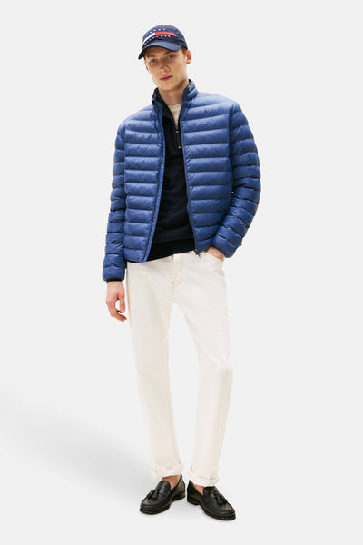 Veste courte bleue de TOMMY HILFIGER, portée avec un pull noir, un pantalon blanc et des mocassins noirs à glands.