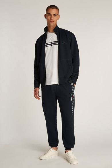 Marineblauwe hoodie van TOMMY HILFIGER, gedragen over een wit gestreept T-shirt met een bijpassende joggingbroek.
