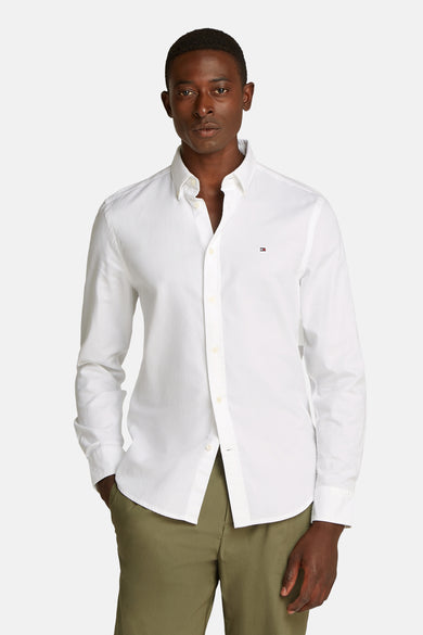 Chemise blanche à manches longues de TOMMY HILFIGER, portée avec un pantalon kaki.