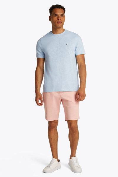 Lichtblauw T-shirt met korte mouwen van TOMMY HILFIGER, gedragen met een roze korte broek en witte sneakers.