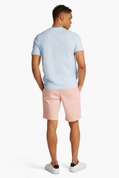 T-shirt à manches courtes bleu clair de TOMMY HILFIGER, porté avec un short rose et des baskets blanches, vue de dos.