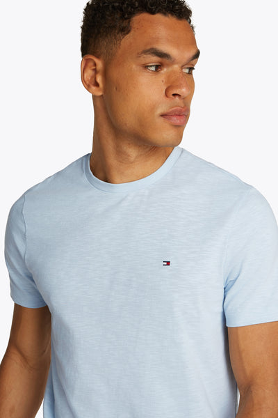 T-shirt bleu clair à manches courtes de Tommy Hilfiger, sur un homme, avec le logo de la marque sur la poitrine.
