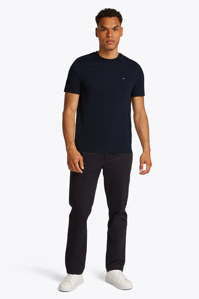 Donkerblauwe T-shirt met korte mouwen van TOMMY HILFIGER, gedragen met een donkere broek en witte sneakers.