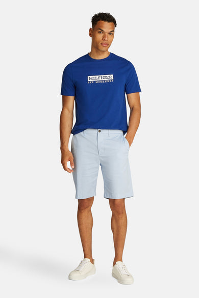 Lichtblauw korte broek van TOMMY HILFIGER, gedragen met een blauw T-shirt met logo en witte sneakers.