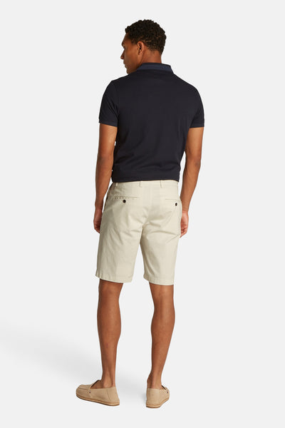 Ecru korte broek van TOMMY HILFIGER, met achterzakken, gedragen met een marineblauw poloshirt en beige espadrilles.