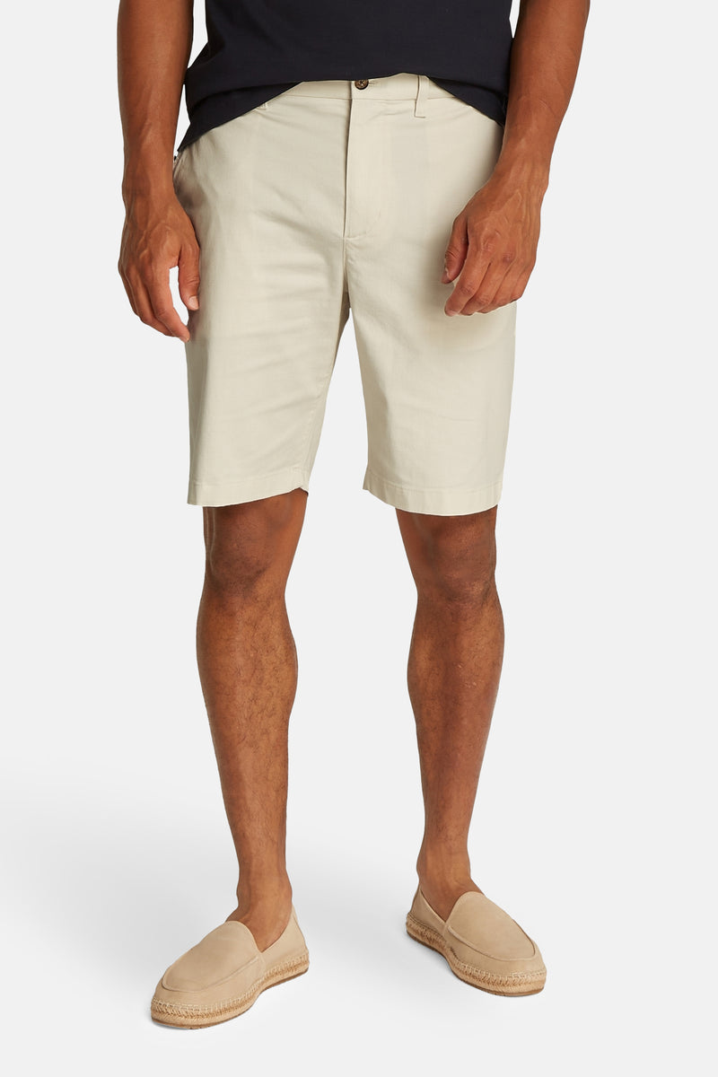 Ecru korte broek van TOMMY HILFIGER, gedragen met zandkleurige loafers en een effen zwart T-shirt.