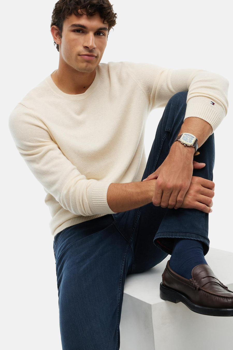 Blue black straight-leg denim jeans by DENTON, worn with cream sweater and brown loafers, side view lifestyle shot
