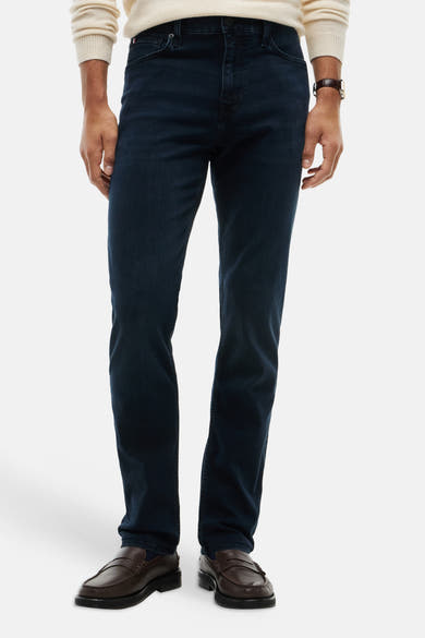 Dark blue straight-leg denim jeans with slim fit, worn by model in front view, paired with cream sweater and brown loafers